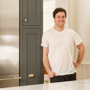 Photo of Nick Lowe, standing by a kitchen cabinet